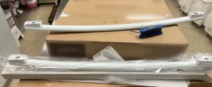 Broken GE freezer door handle beside the new replacement handle still in its packaging, Langley, BC